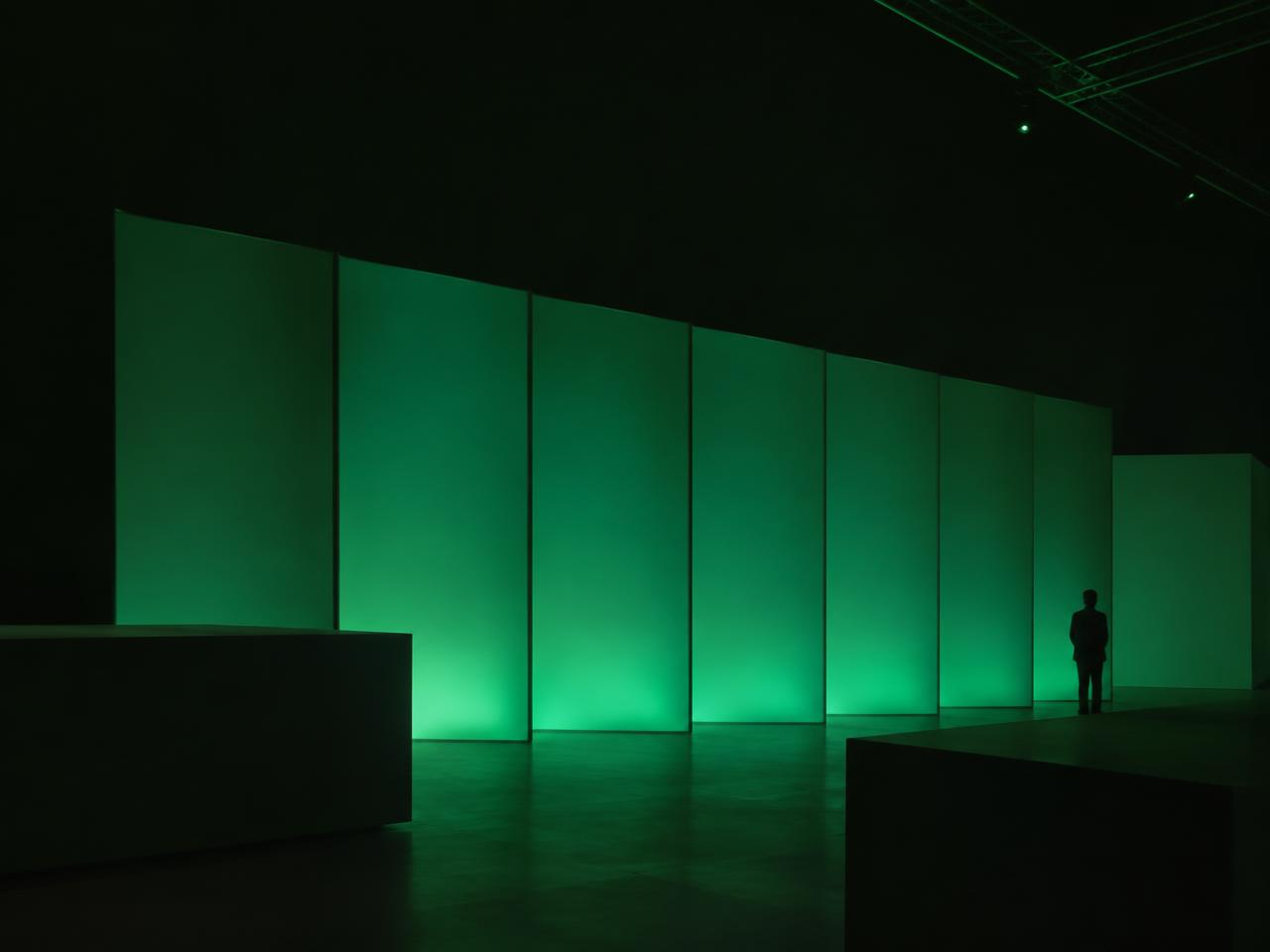 Dark event space with illuminated deep green panels used for brand activation