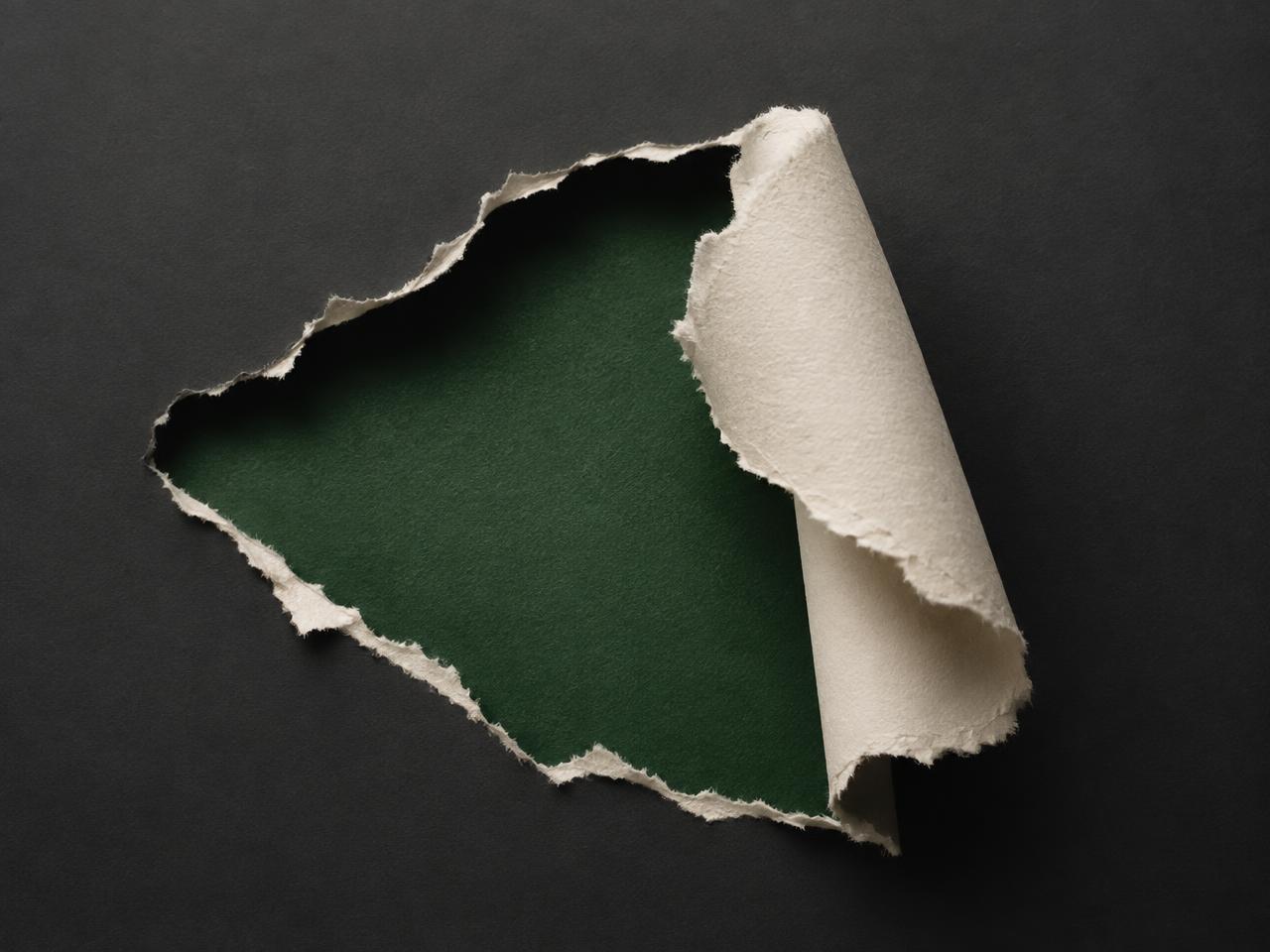 Off-white paper torn back to reveal deep green, representing a rebrand